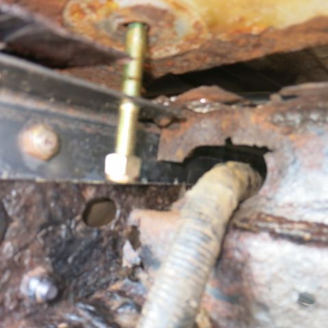 1995 Ford Bronco - Rusted vehicle frame shows a bolt and a hose, indicating wear and tear.