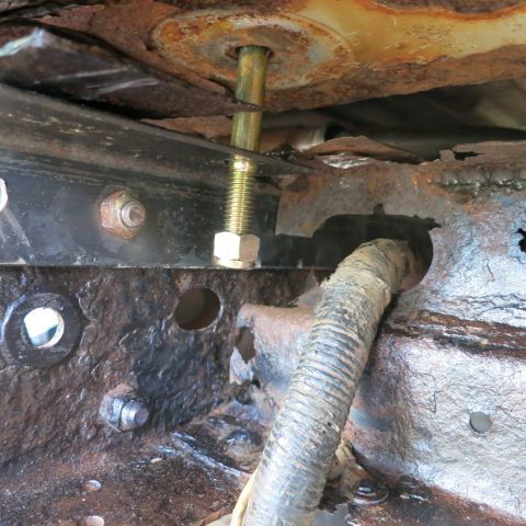1995 Ford Bronco - This image shows significant rust on a vehicle's undercarriage, focusing on a bolt and a section of wiring.