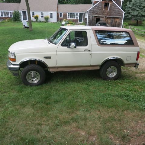 1995 Ford Bronco - A side view of a 1995 Ford Bronco is captured in a grassy yard with a house and barn in the background.