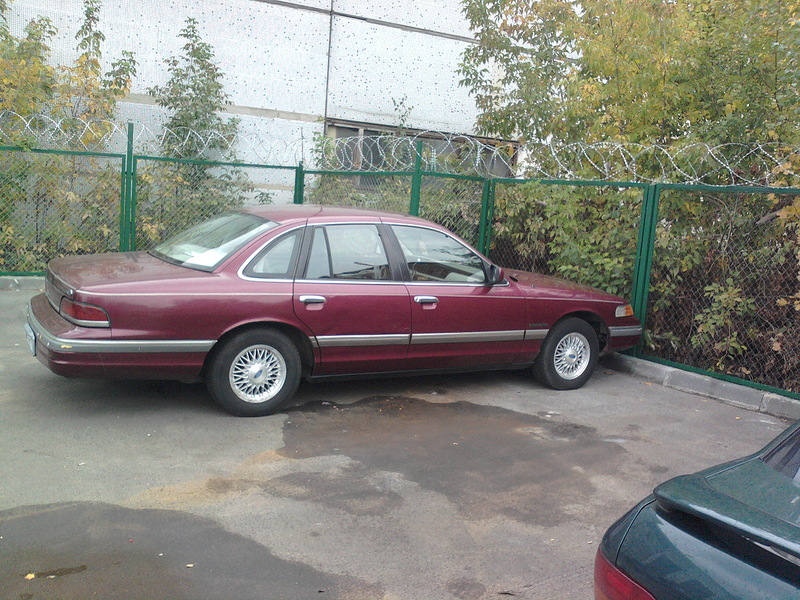 Maroon 1992 Ford Crown Victoria parked on asphalt, side view. Another car is partially visible in the foreground