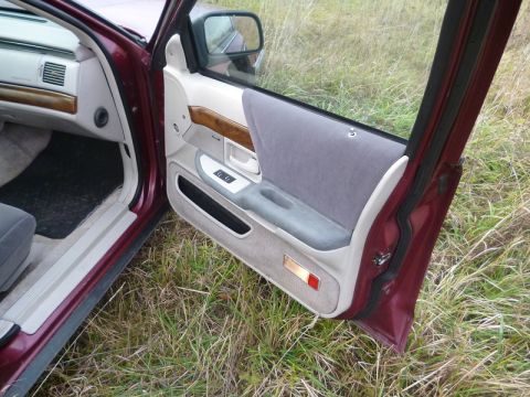 1992 Ford Crown Victoria - The interior door panel of a car, fabric upholstery and wood accents, is shown with the door ajar.