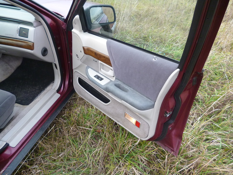 Interior shot of a car's front passenger door, showing the door panel with fabric and wood trim, and the dashboard area