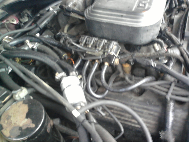 Blurry engine bay photo showing V8 fuel injectors, hoses, and an inline fuel filter