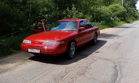 1992 Ford Crown Victoria - Red 1992 Ford Crown Victoria with driver's door ajar, parked on a rural road.