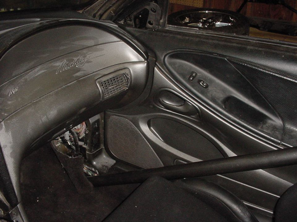 Gray dashboard with 'Mustang' script, showing exposed wiring and a roll bar