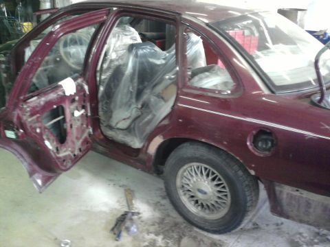 1992 Ford Crown Victoria - This maroon sedan appears to be undergoing repairs or restoration, with its interior covered in protective plastic.