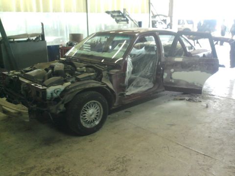 1992 Ford Crown Victoria - A maroon sedan is in a repair shop with its hood off and doors open.