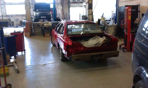 1992 Ford Crown Victoria - Red sedan in a garage with its trunk open. Another vehicle is visible on a lift.