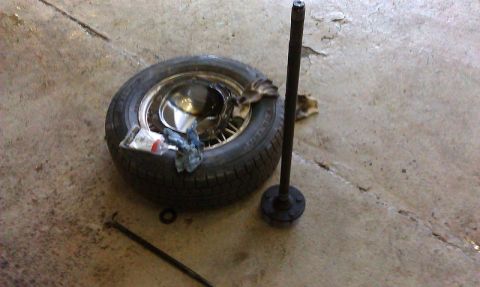 1992 Ford Crown Victoria - An axle shaft and a spare tire are shown on a concrete floor, possibly in a garage or workshop.