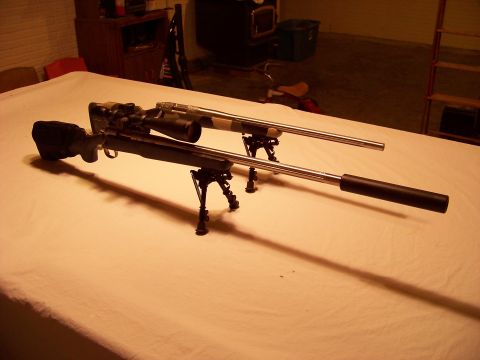 1995 Mercury Grand Marquis - Two rifles are displayed on a table, each equipped with a scope and bipod.