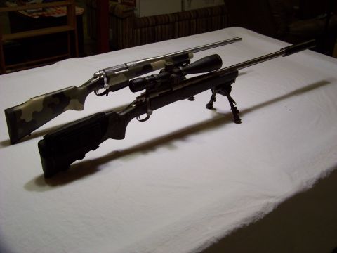 1995 Mercury Grand Marquis - Two rifles are displayed on a white tablecloth, one a camouflage stock and a scope with a bipod.