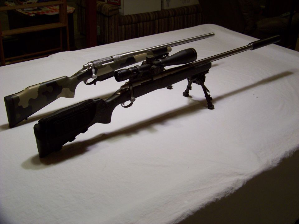 Two rifles, one with camouflage stock and scope, on a white tablecloth