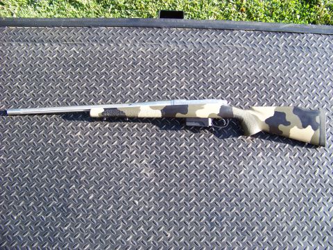 1995 Mercury Grand Marquis - A rifle with a camouflage stock and stainless steel barrel is displayed on a textured surface.