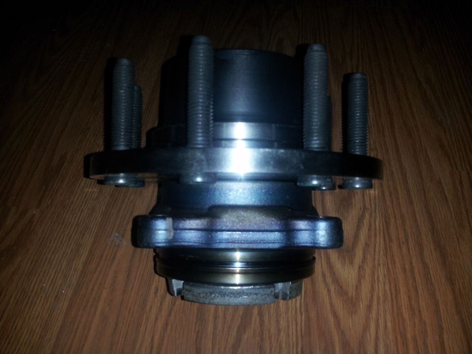 Wheel hub assembly with five studs, resting on a wooden surface
