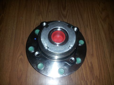 1988 Ford Bronco - A wheel hub assembly is shown, a red center and green bolt caps on a wooden surface.