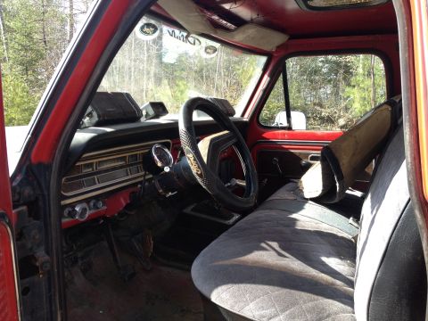 1979 Ford Bronco - The interior of a red 1979 Ford Bronco features a dashboard with gauges and worn seats.
