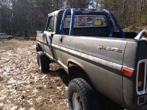 1979 Ford Bronco - This weathered pickup truck features a roll bar and various stickers on its rear window.