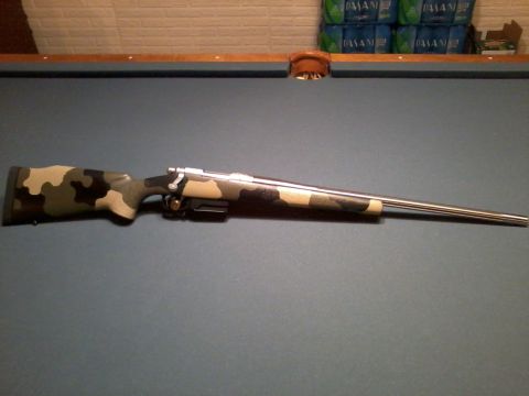 1995 Mercury Grand Marquis - A rifle with a camouflage stock is displayed on a pool table, with bottles of water in the background.