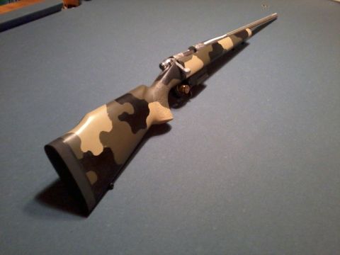 1995 Mercury Grand Marquis - Rifle with camouflage stock and metal barrel shown from the side.
