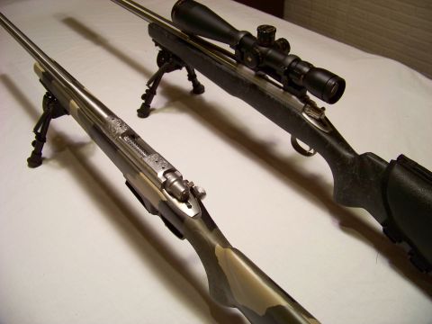 1995 Mercury Grand Marquis - Two rifles are displayed on a white surface, each equipped with a bipod for stability.