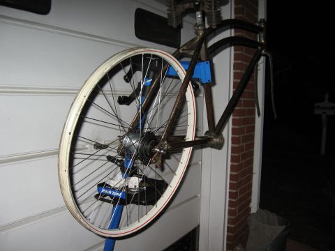 1994 Ford Bronco - A bicycle frame and wheel are held by a blue repair stand, attached to a white wall with brick accents.