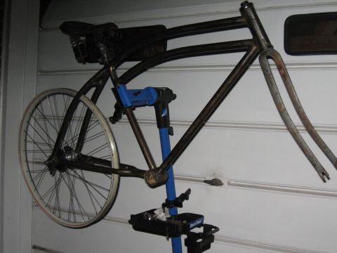 1994 Ford Bronco - A bicycle frame, fork, and rear wheel are mounted on a blue Park Tool repair stand against a white wall.