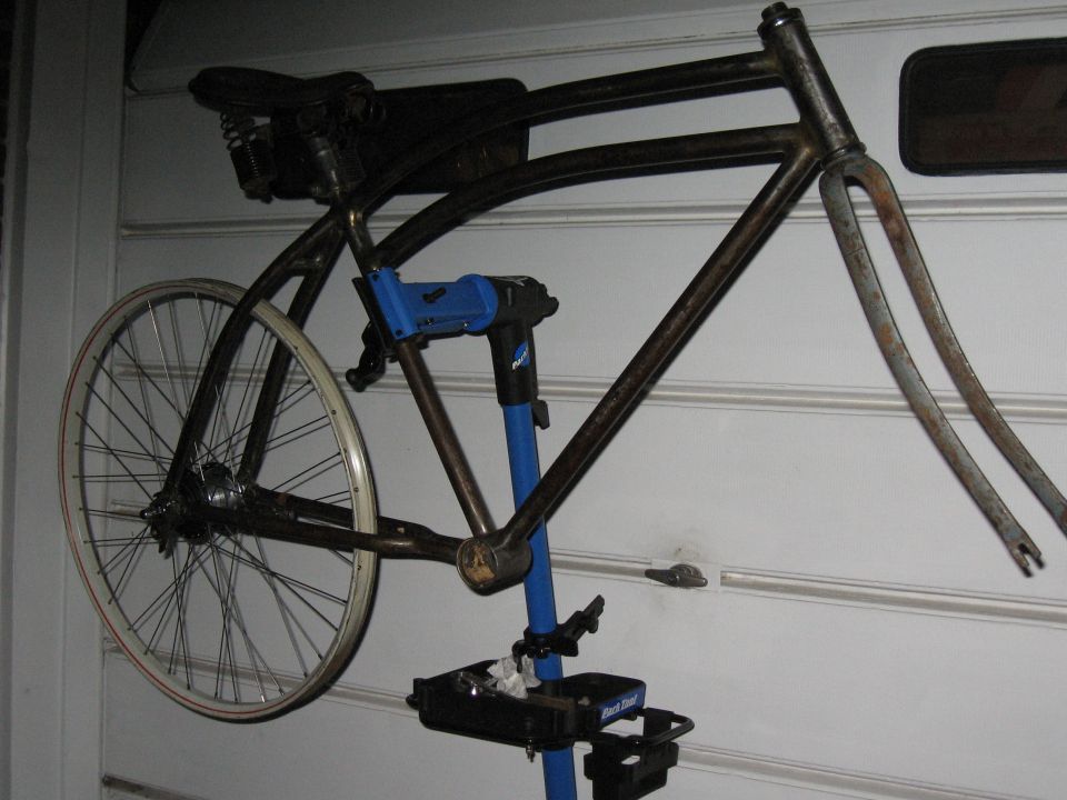 Bicycle frame and wheel on a blue repair stand. Park Tool logo visible
