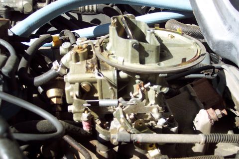 1991 Ford LTD Crown Victoria - A detailed view of a vehicle's carburetor, showing its intricate mechanical components and surrounding engine parts.