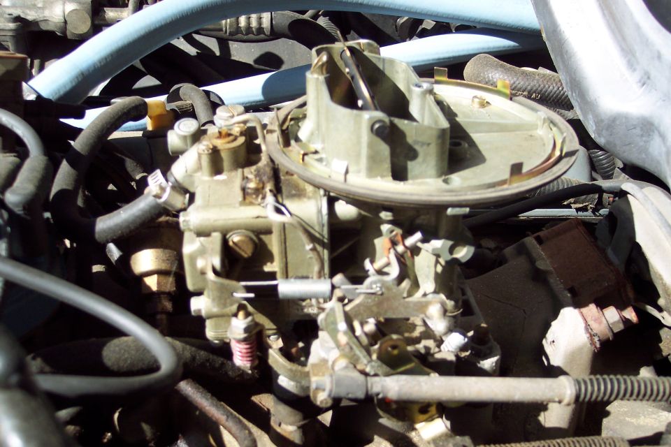 close-up of a car's carburetor with hoses and engine parts visible
