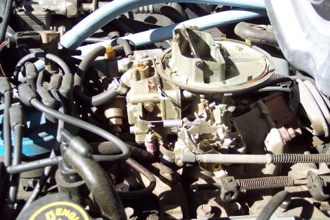 1991 Ford LTD Crown Victoria - A detailed view of a carburetor and surrounding engine components.