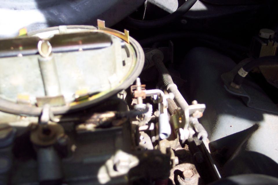 Close-up of a carburetor with linkages and hoses visible