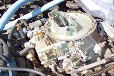 1991 Ford LTD Crown Victoria - A close-up view of a vehicle's carburetor and surrounding engine components.