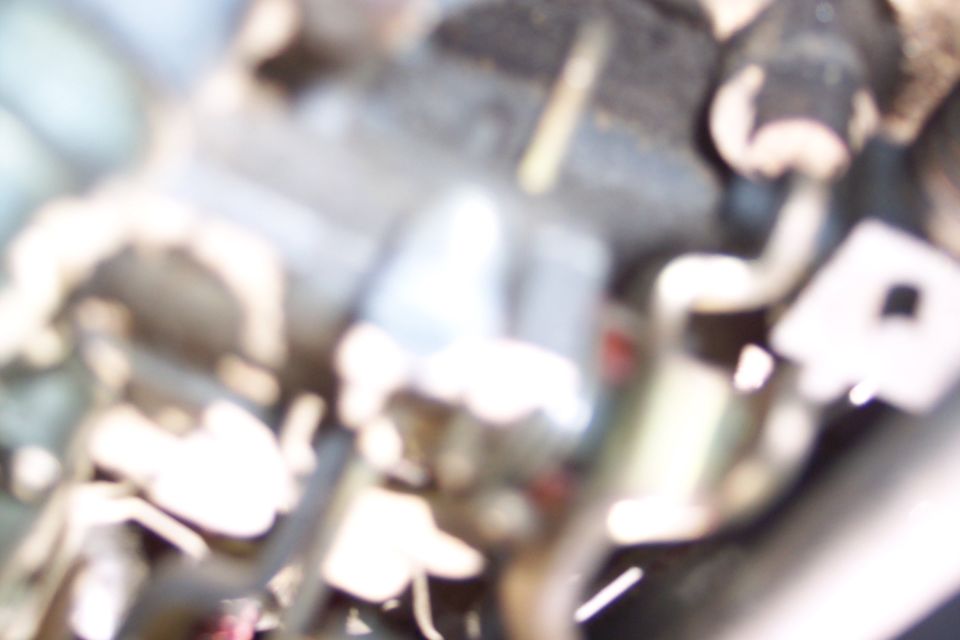 Close-up of blurry engine bay parts with hoses and metal components