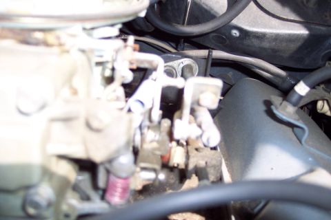 1991 Ford LTD Crown Victoria - A detailed view of the carburetor and associated engine parts, showing mechanical linkages and hoses.