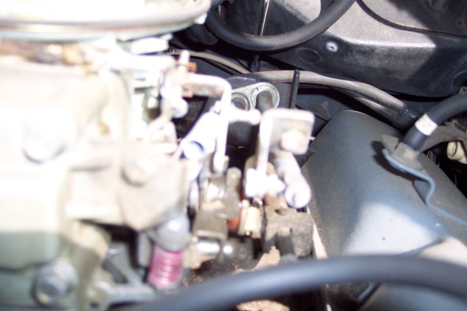 close-up of carburetor linkage and engine bay components