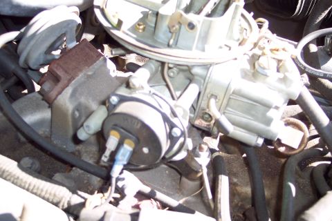 1991 Ford LTD Crown Victoria - Close-up view of an engine carburetor, showing various mechanical and electrical components.