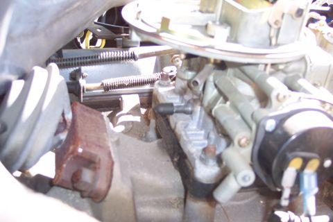 1991 Ford LTD Crown Victoria - Detail of an engine's carburetor and associated parts, showing mechanical linkages and wiring.