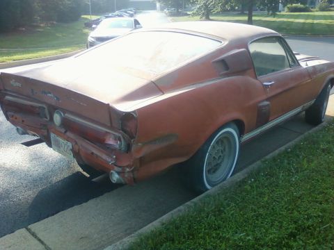 1971 Ford Ranchero - Rear view of a damaged orange muscle car, possibly a 1969 model, parked on the side of the road.