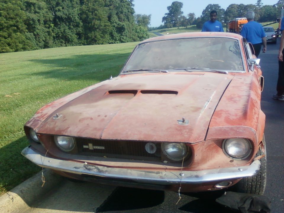 Front view of a dusty red 1967 Ford Mustang with hood scoops