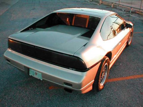 1994 Ford Crown Victoria - The rear of a silver Pontiac Fiero is shown from a low angle, with the sun setting.