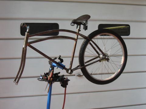 1994 Ford Bronco - A bicycle frame, showing its rusty patina and vintage saddle, is held on a repair stand against a garage door.