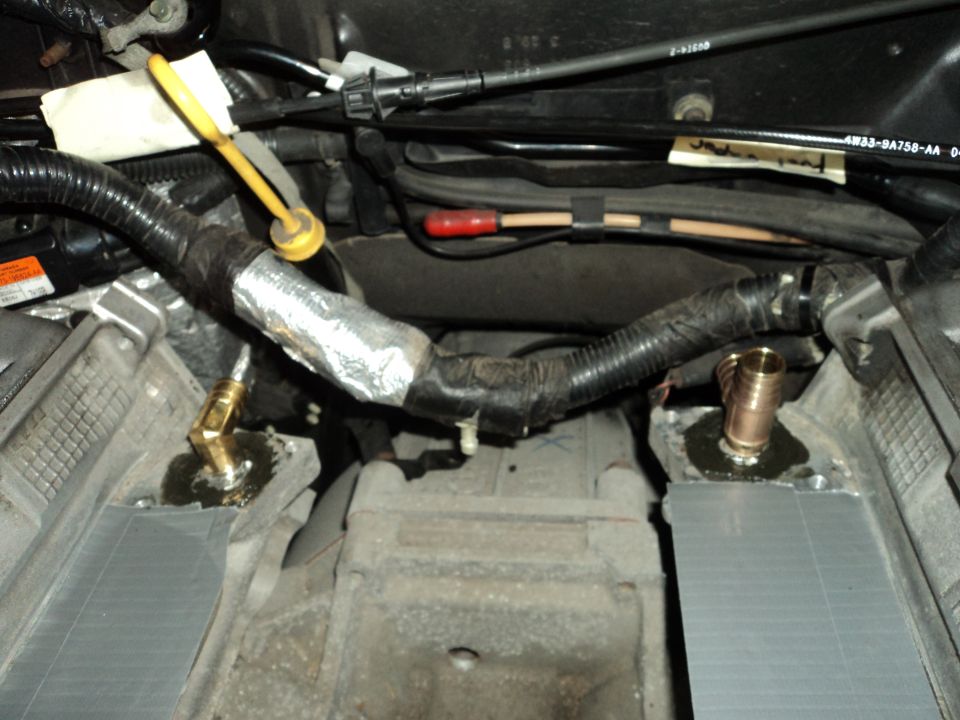 engine bay with new brass fittings and hoses, some silver insulation tape on a bundle of wires