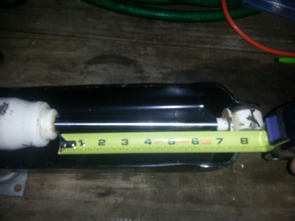 Shock absorber being measured with a tape measure showing approximately 8 inches