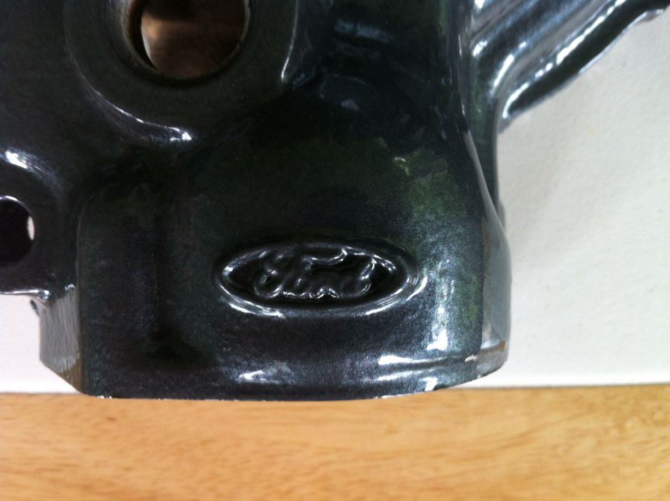 Close-up of a dark metallic Ford emblem on a cast metal engine component