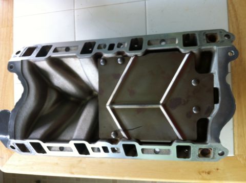 1992 Ford Bronco - An aluminum intake manifold with visible internal runners and a metal plate a hexagonal pattern is shown.