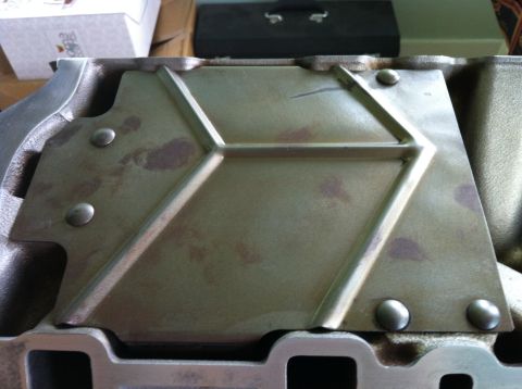 1992 Ford Bronco - This is a close-up view of a metal engine component, possibly an intake manifold, showing its textured surface and fastening rivets.