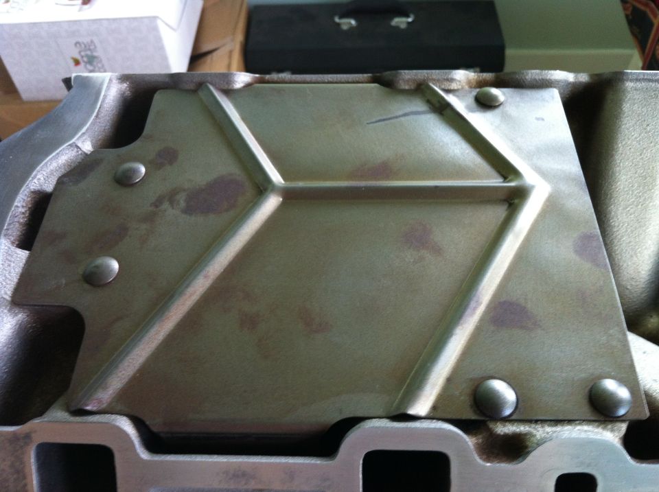 Close-up of a metal engine part with a diamond pattern and rivets