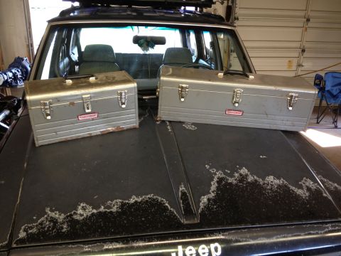1988 Ford Bronco - Two toolboxes sit on the hood of a Jeep Cherokee XJ, which has significant paint damage on its hood.
