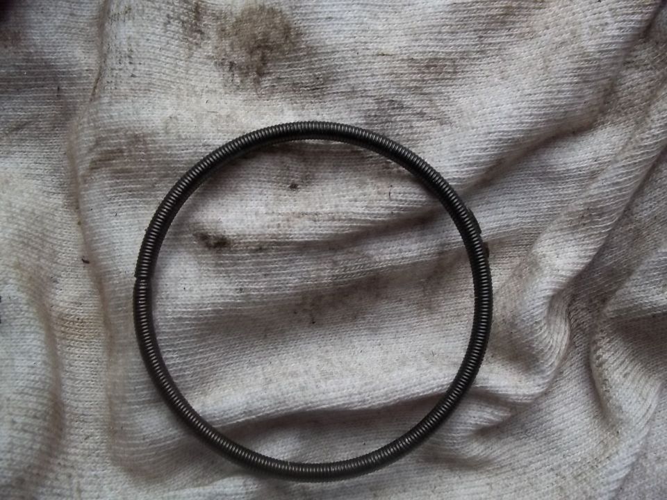 Close-up of a coiled metal spring lying on a stained white cloth