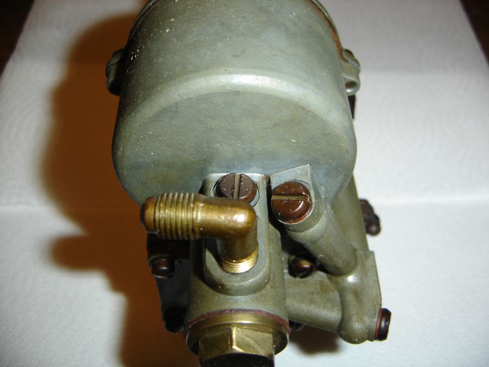 Carburetor part with brass fittings and screws, close-up view